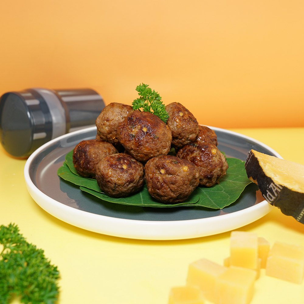 EasyGrater mit Cheesy Meatballs vor orangefarbenem Hintergrund