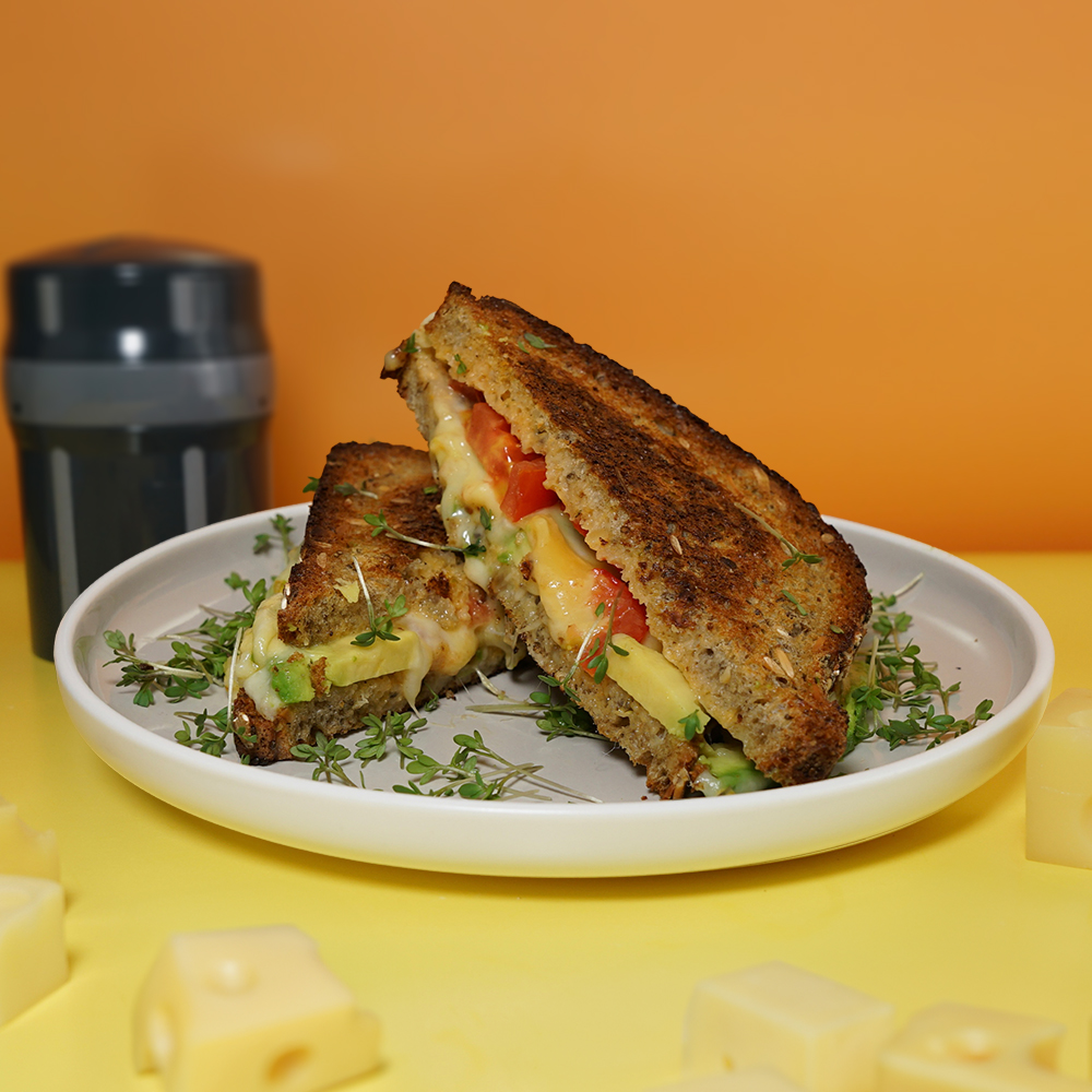 EasyGrater mit Grilled Cheese Sandwich vor orangefarbenem Hintergrund