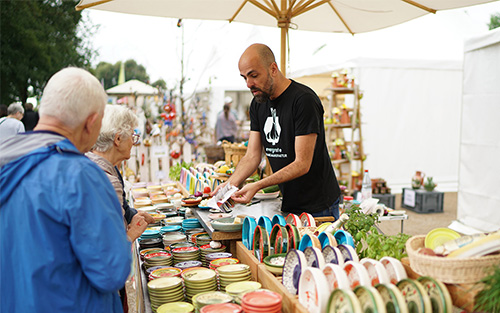 Beratung und Verkauf von Keramikreiben an einem Marktstand