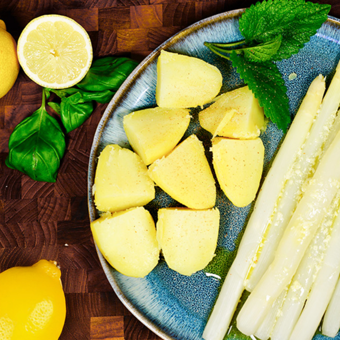 Spargel auf einem Teller neben Kartoffeln mit Soße